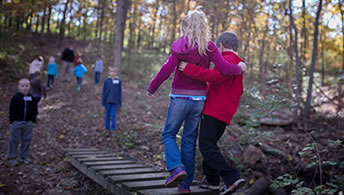 kids walking on bridge in woods